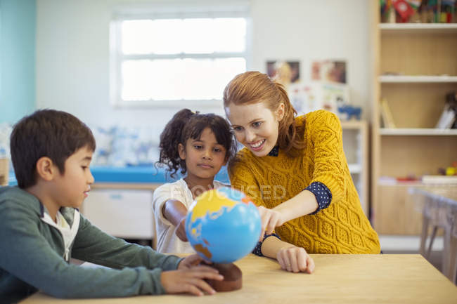 Schüler und Lehrer begutachten Globus im Klassenzimmer — Stockfoto