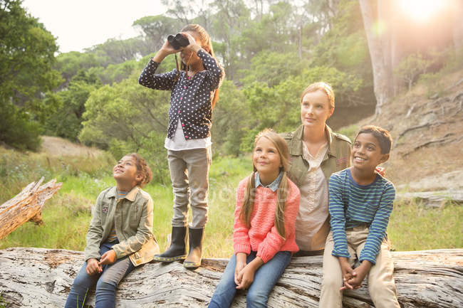 Students and teacher using binoculars in forest — Stock Photo