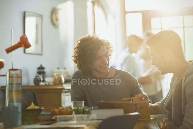 Young men college students studying at sunny dining table — Stock Photo
