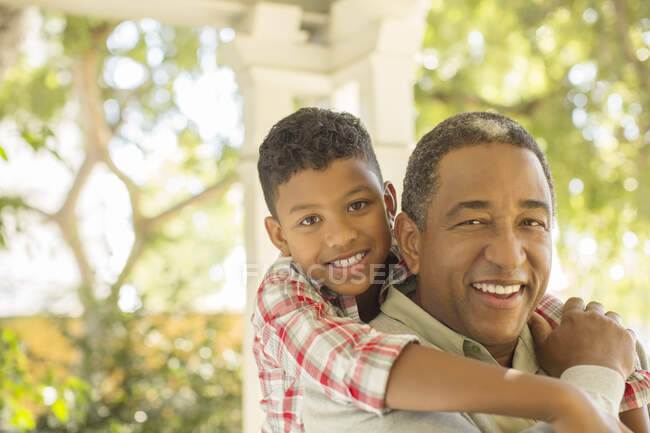 Портрет улыбающегося дедушки и внука, обнимающихся на улице — стоковое фото