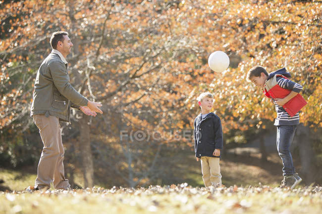 Pai e filhos jogando futebol no parque de outono — Fotografia de Stock