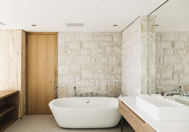 Muri di pietra dietro vasca da bagno in bagno moderno — Foto stock