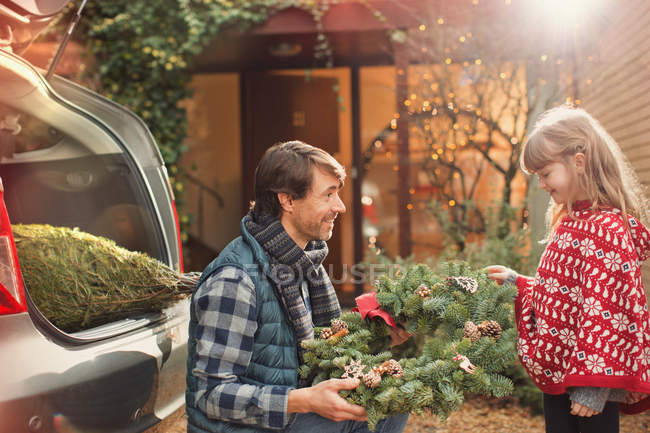 Father and daughter with Christmas wreath outside car — Stock Photo