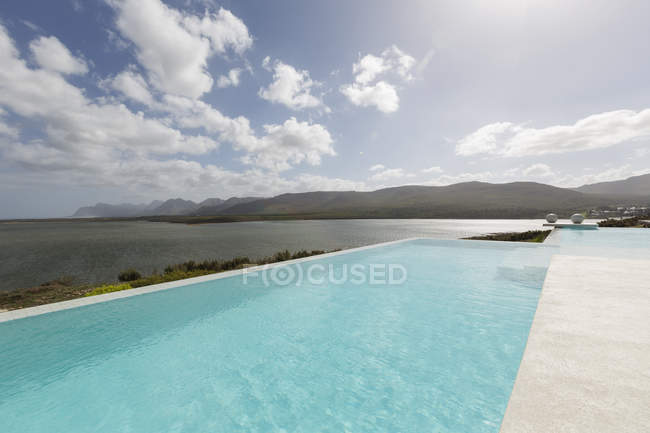 Soleggiata, tranquilla piscina a sfioro con vista sull'oceano — Foto stock