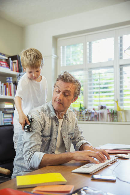 Хлопчик відволікає батька на роботі в домашньому офісі — стокове фото