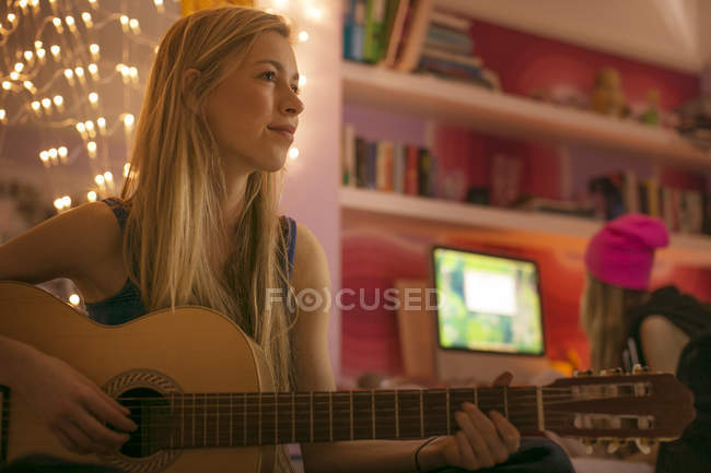 Ragazza adolescente che suona la chitarra in camera da letto — Foto stock