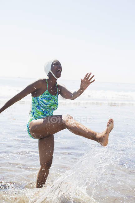 Happy black woman splashing in ocean surf — Stock Photo