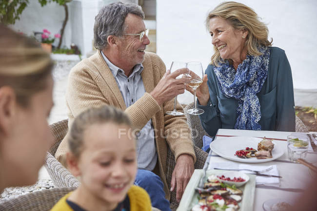 Feliz casal sênior brindar copos de vinho branco no pátio almoço — Fotografia de Stock