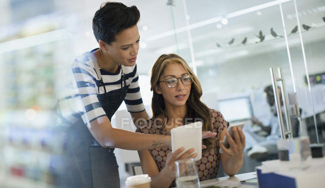 Creative businesswomen using smart phone and digital tablet in office — Stock Photo
