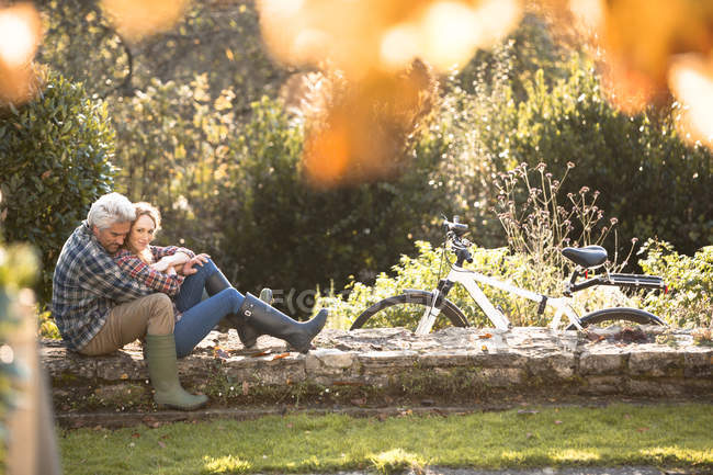 Affectionate couple hugging on stone wall in autumn park — Stock Photo