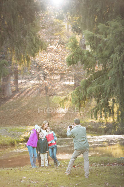 Отец фотографирует семью с телефоном в парке — стоковое фото