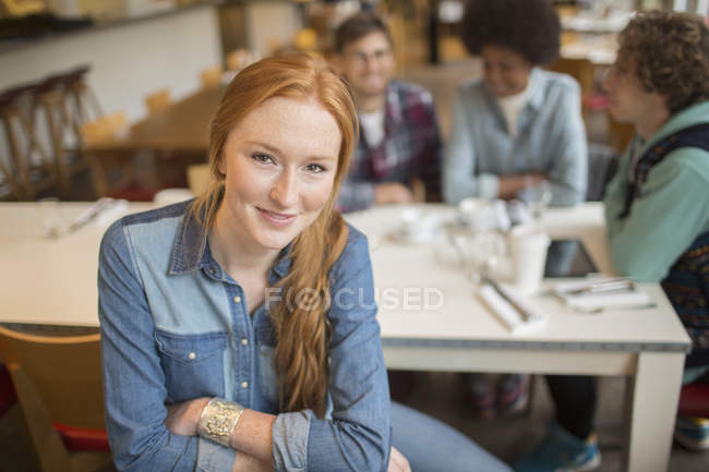 Feliz jovem mulher sentada com amigos no café — Fotografia de Stock