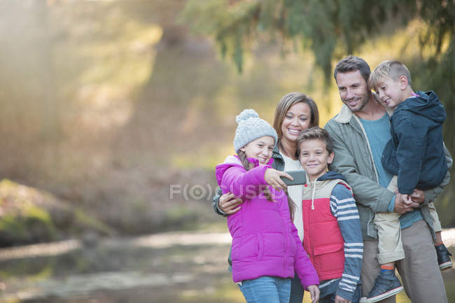 Family taking selfie with camera phone in woods — Stock Photo