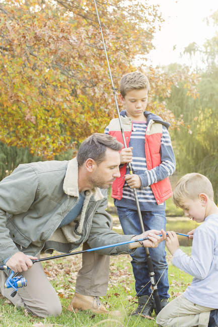 Padre enseñando a los hijos a preparar cañas de pescar - foto de stock