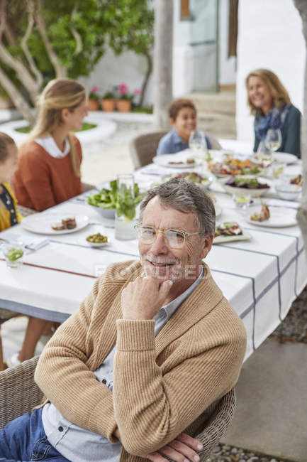 Портрет улыбающегося пожилого человека, наслаждающегося обедом в патио — стоковое фото