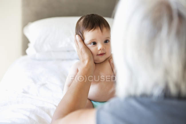 Woman holding granddaughter on bed — Stock Photo