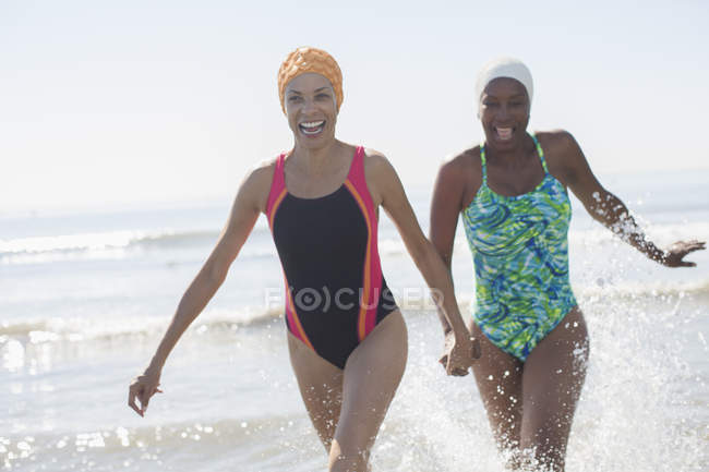 Lesbienne ludique couple éclaboussures dans l'océan surf — Photo de stock