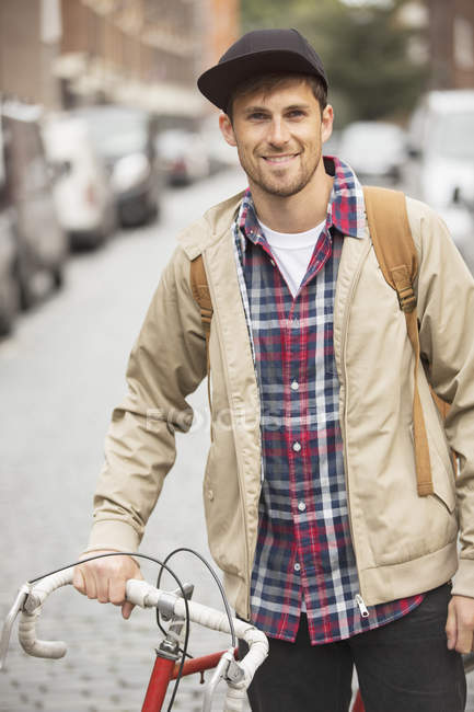 Hombre empujando bicicleta en la calle de la ciudad - foto de stock