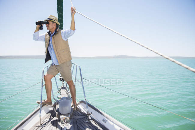 Homem mais velho olhando binóculos na borda do barco — Fotografia de Stock