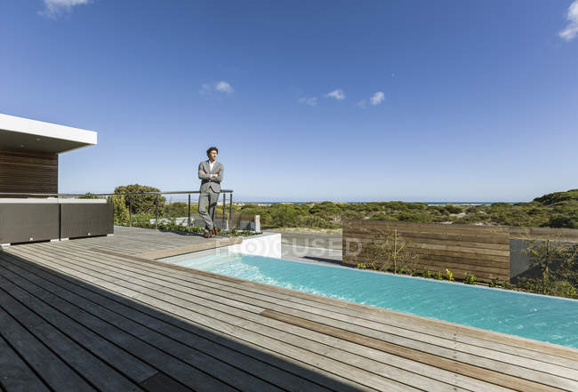 Uomo d'affari sul soleggiato patio moderno e lussuoso con piscina a sfioro — Foto stock