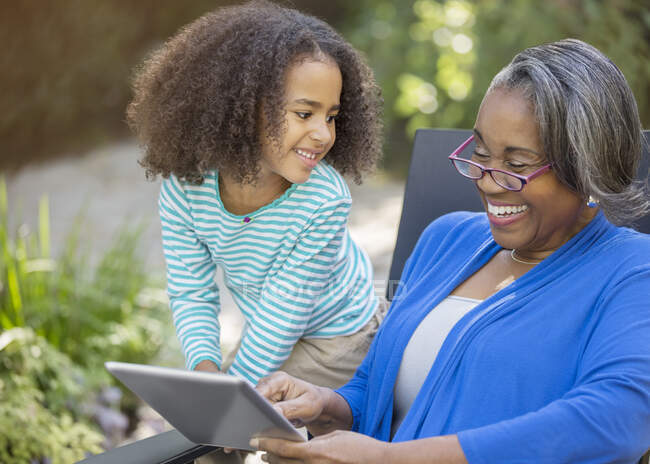 Grandmother and granddaughter using digital tablet on patio — Stock Photo
