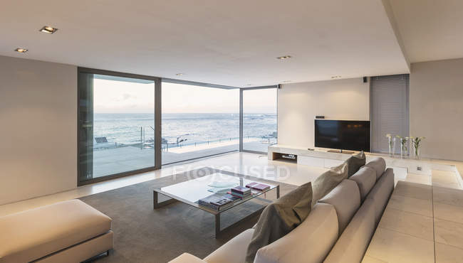 Moderno e minimalista soggiorno di lusso con porte finestre aperte sull'oceano — Foto stock