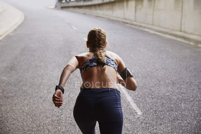 Вмістити жіночу бігунку з mp3 плеєр пов'язкою, що працює на міській вулиці — стокове фото