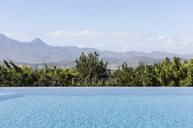 Tranquillo lusso piscina a sfioro con soleggiata vista sulle montagne — Foto stock