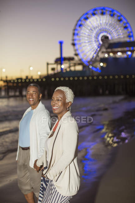 Senior couple walking on beach at sunset — Stock Photo