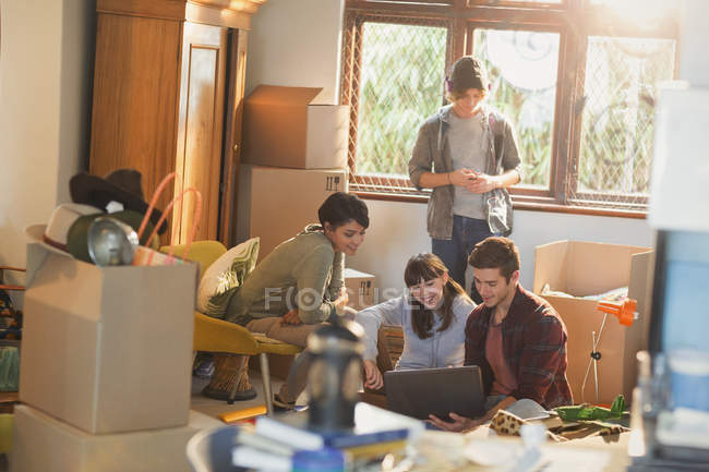 Young couples roommates using laptop surrounded by moving boxes — Stock Photo