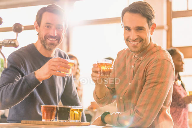 Портрет улыбающихся мужчин друзья дегустируют пиво в баре микропивоварни — стоковое фото