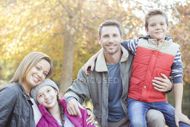 Portrait smiling family in front of tree with autumn leaves — Stock Photo