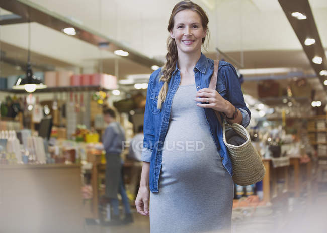 Portrait smiling pregnant woman walking in shop — Stock Photo