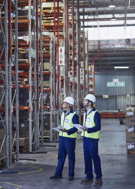 Workers with clipboards looking away in distribution warehouse — Stock Photo
