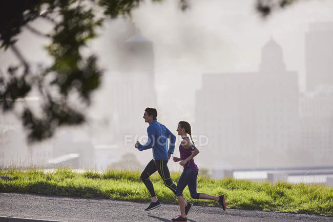 Пара бегунов бегает по солнечной городской улице — стоковое фото