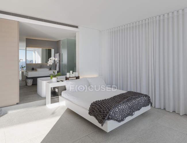 Кровать в современной, роскошной витрине интерьера спальни с ванной комнатой — стоковое фото