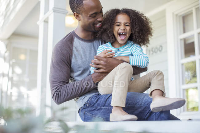 Отец щекочет дочь на крыльце — стоковое фото
