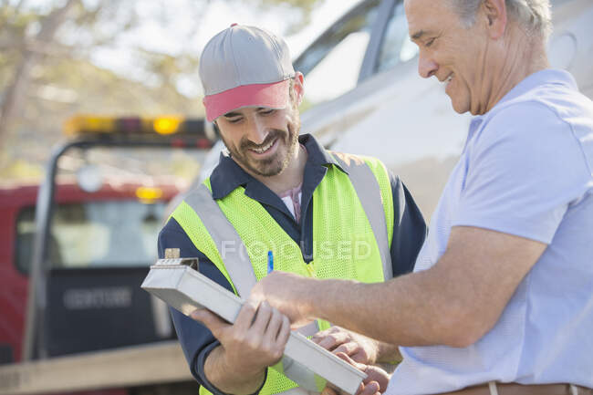 Man signing paperwork for roadside mechanic — Stock Photo