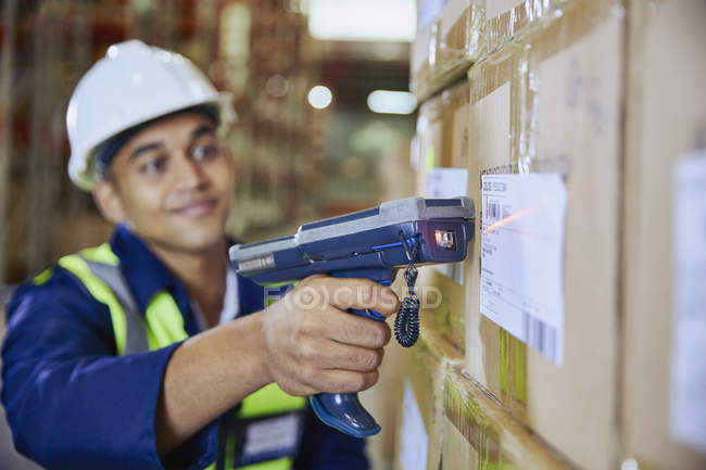Worker with scanner scanning barcode on box in distribution warehouse — Stock Photo