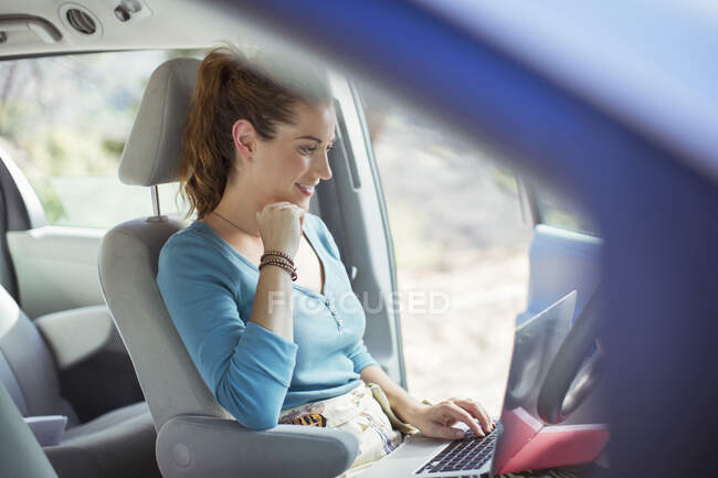 Woman using laptop in car — Stock Photo