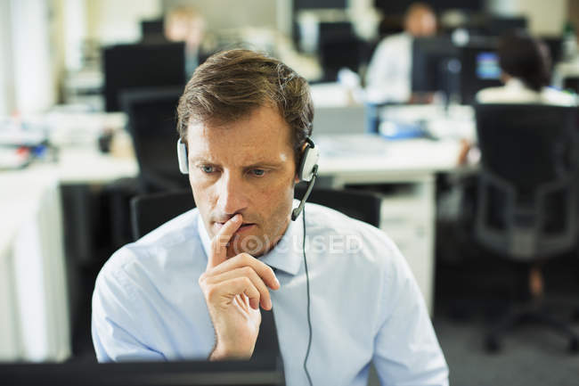 Homem de negócios usando fone de ouvido no escritório — Fotografia de Stock