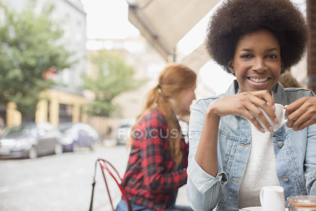 Жінка п'є каву на тротуарі кафе — стокове фото