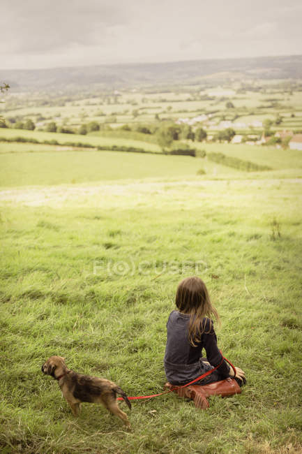 Дівчина з цуценяткою у сільській, зеленій місцевості — стокове фото