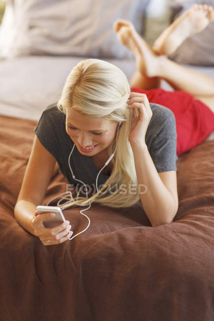 Женщина слушает mp3 плеер на кровати — стоковое фото