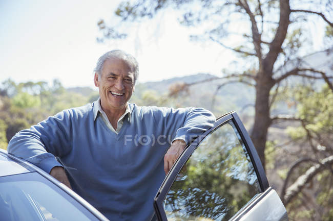 Porträt eines glücklichen Seniors, der sich an Auto lehnt — Stockfoto