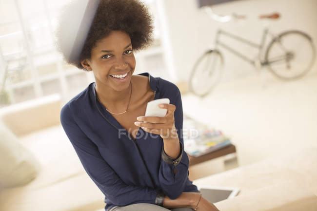 Жінка за допомогою мобільного телефону у вітальні на дому — стокове фото