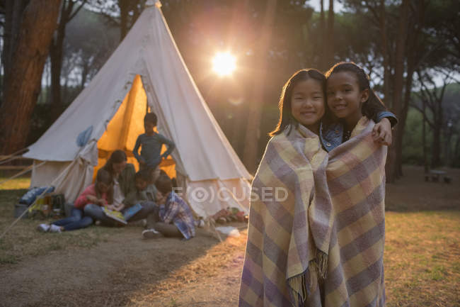 Girls wrapped in blanket at campsite — Stock Photo
