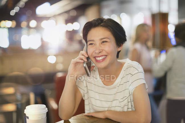 Улыбающаяся молодая женщина разговаривает по телефону в кафе — стоковое фото