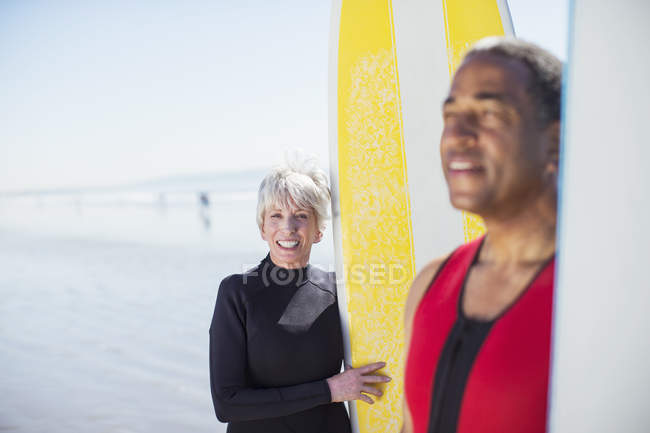 Retrato de pareja mayor con tablas de surf en la playa - foto de stock