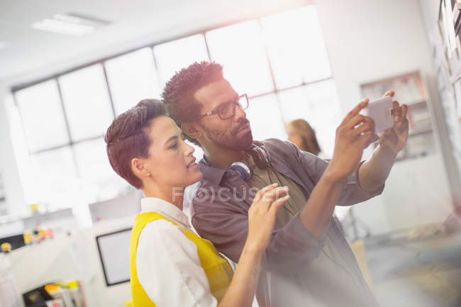 Focused creative business people using camera phone in office — Stock Photo
